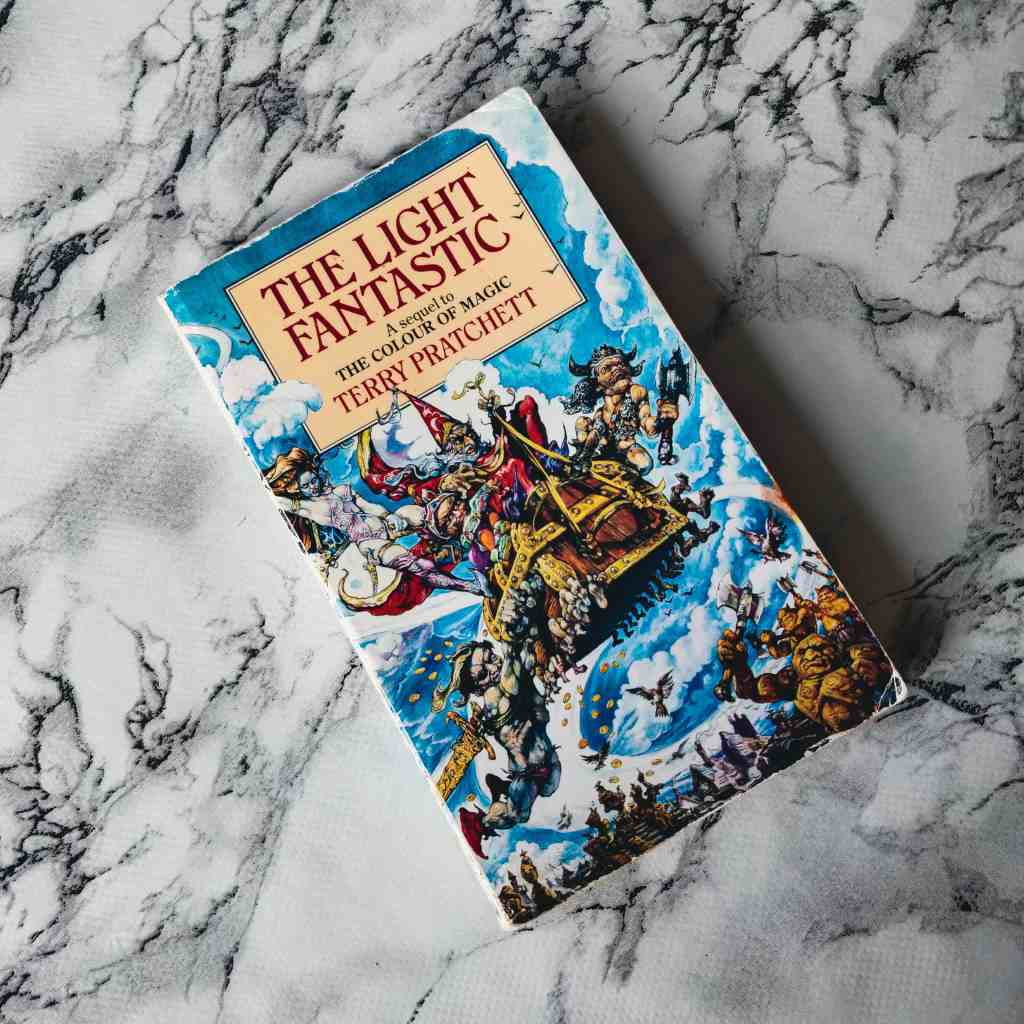 The Discworld novel The Light Fantastic by Terry Pratchett, against a white and black marble background.